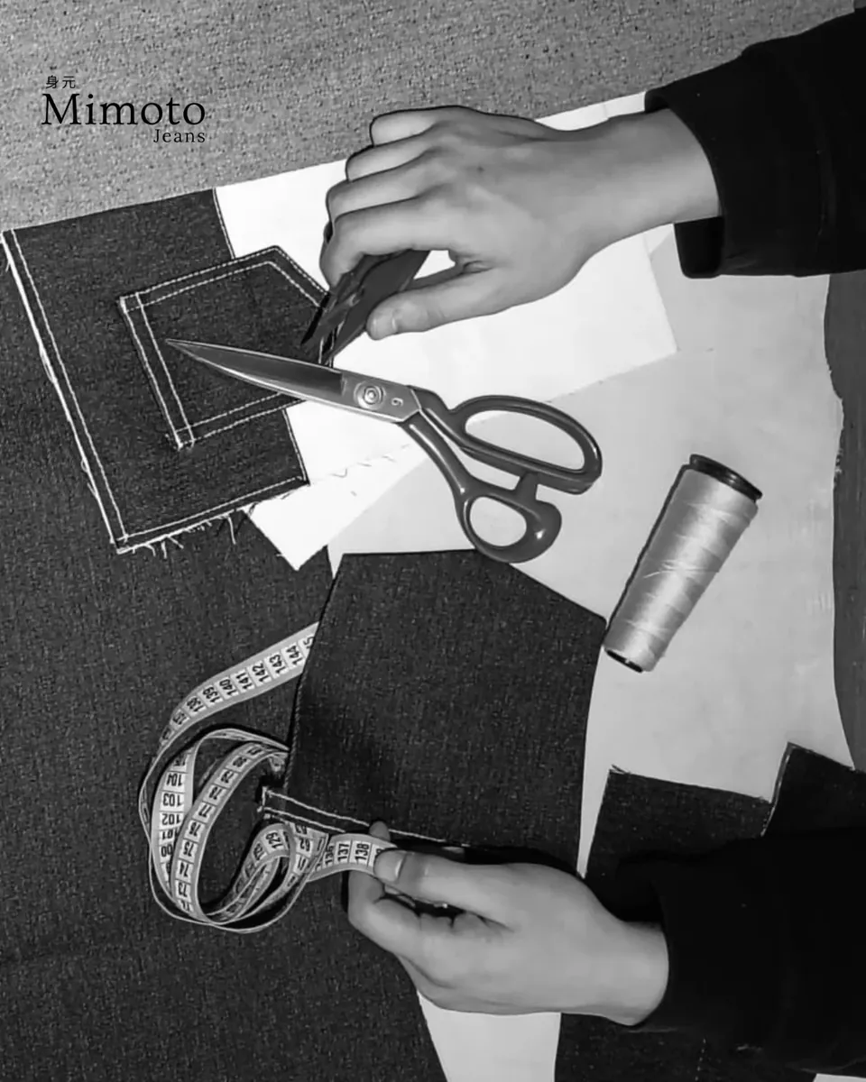 Tijeras, cinta métrica, patrones de papel y piezas de denim sobre la mesa de trabajo